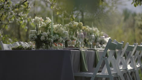 Schöne-Blumendekoration-Auf-Dem-Tisch-Im-Blühenden-Garten-Am-Frühlingstag,-Catering-Für-Open-Air-Veranstaltung